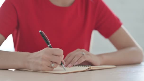 Κοντινό πλάνο της νεαρής γυναίκας που γράφει στο σημειωματάριο - Πλάνα, βίντεο