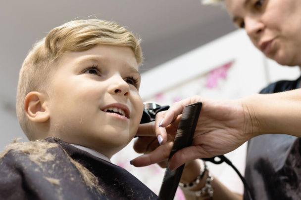 Низкий угол зрения на мальчика, стригущегося в парикмахерской.  - Фото, изображение