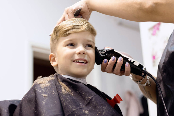 Blond little boy having a haircut at hair salon.  - Foto, imagen