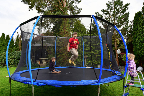 The children bought a new trampoline and put it in the yard and jump on it. - Fotoğraf, Görsel