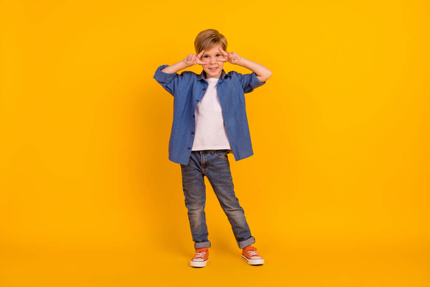 Full size photo of cheerful positive boy arms fingers demonstrate v-sign near eyes isolated on yellow color background. - Foto, Bild
