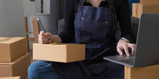 Starting small businesses SME owners female entrepreneurs Write the address on receipt box and check online orders to prepare to pack the boxes, sell to customers, sme business ideas online - Photo, Image