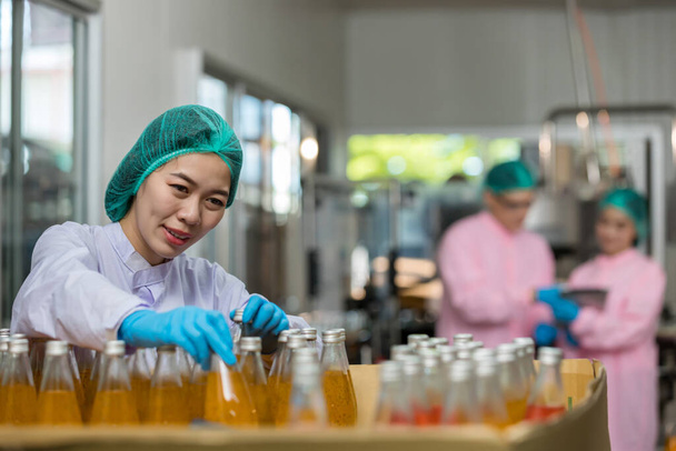 Woman worker using Checking quality or checking stock of products in beverage factory. Worker QC working in a drink water factory - Foto, imagen