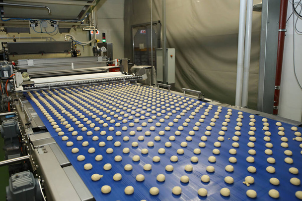 Close up of automated biscuit cookies shape forming machine. Selective focus. machine for making cookies in the factory. Conveyor belt with Cookie dough - 写真・画像
