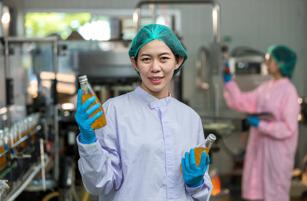 Woman worker using Checking quality or checking stock of products in beverage factory. Worker QC working in a drink water factory - Фото, зображення