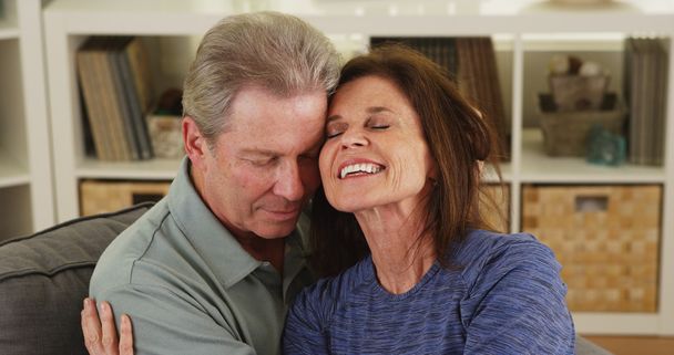 Senior couple cuddling on couch at home - Photo, Image