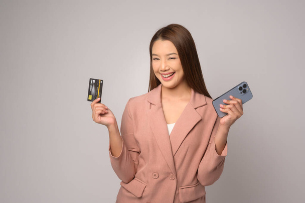 A Young asian woman holding credit card over white background studio, shopping and finance concept. - Φωτογραφία, εικόνα