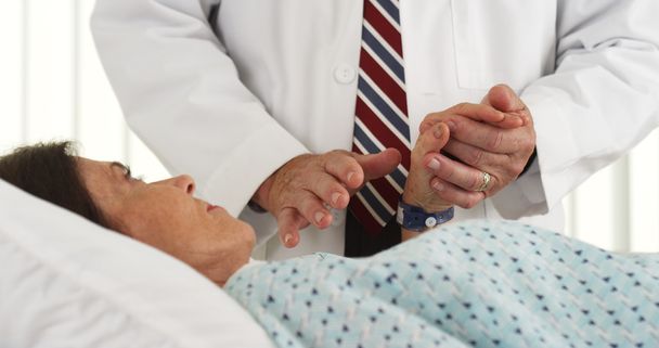 Доктор тримає руку пацієнта і втішає її
 - Фото, зображення