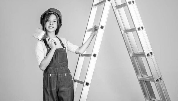 girl kid in hard hat on construction site use ladder and painting brush, builder. - Zdjęcie, obraz