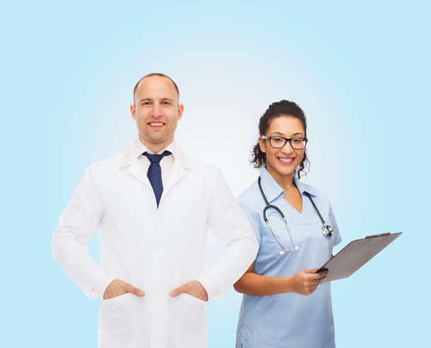 smiling doctors with clipboard and stethoscopes - Zdjęcie, obraz