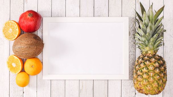 White copy space frame with exotic summer fruits on wooden background. Flat lay - Foto, Bild