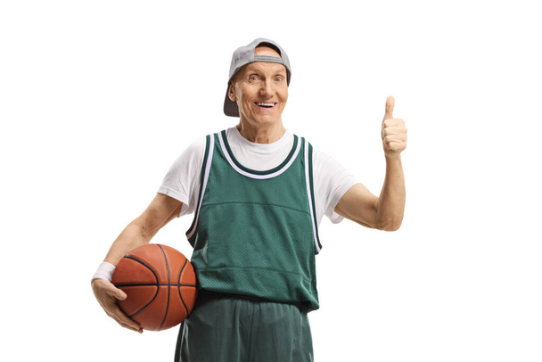 Elderly man in a green jersey holding a basketball and showing thumbs up isolated on white background - Photo, image