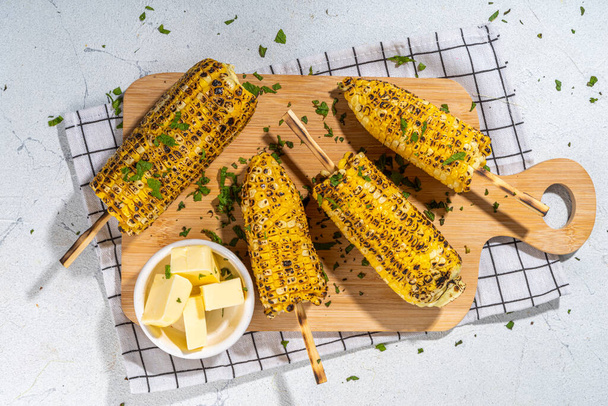 Sweet corn grilled with butter, cheese, cilantro and herbs. Vegetarian, healthy, clean eating barbeque food. Portioned bbq grill corn cobs on white background - Valokuva, kuva