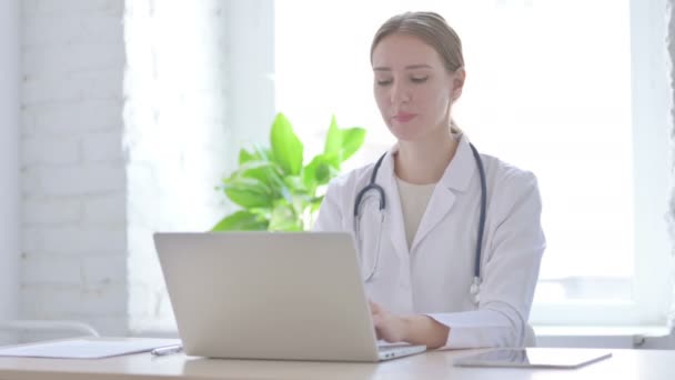 Doctora sonriendo en la cámara mientras está sentada en la clínica - Imágenes, Vídeo
