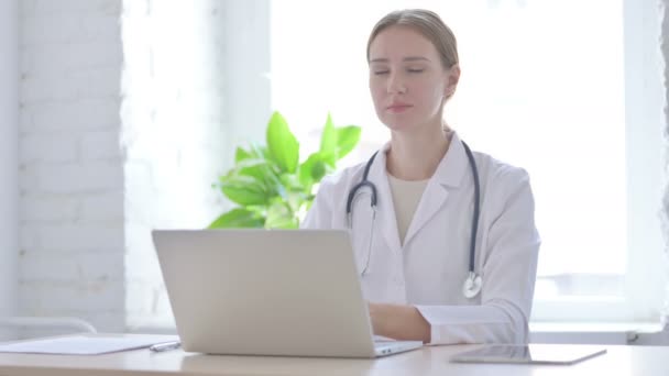 Женщина-доктор показывает пальчики на груди, сидя в клинике - Кадры, видео