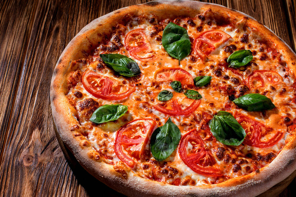 Delicious fragrant pizza with mozzarella, tomatoes and basil with tomato sauce on woden background. - Foto, imagen