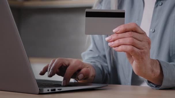 Close-up female wrinkled human hands unknown old woman shopper freelancer holds plastic credit card enter numbers for online bank app paying order in web store transfers savings money online booking - Filmagem, Vídeo
