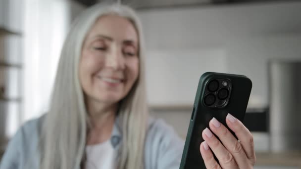 Ηλικιωμένη ξανθιά γκρίζα μαλλιά καυκάσια γιαγιά ώριμη ηλικιωμένη γυναίκα κρατήστε το κινητό τηλέφωνο κουβέντα online καλώντας εικονική συνομιλία βίντεο με την οικογένεια μακρινή συνάντηση χρησιμοποιώντας τη σύγχρονη τηλεφωνική ψηφιακή ασύρματη τεχνολογία - Πλάνα, βίντεο