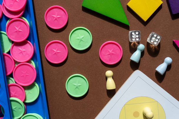 Различные настольные игры, фигурки, кубики, части на коричневом столе. Домашние развлечения, игры в помещении - Фото, изображение