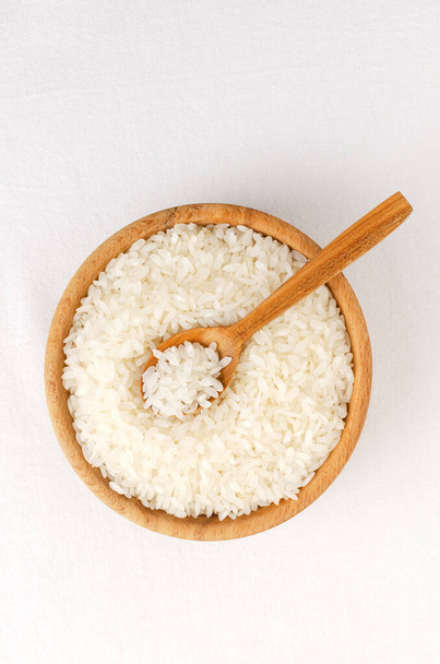 Dry camolino rice in a wooden bowl with a spoon. The concept of healthy eating. Rustic style. Selective focus. Vertical orientation. Top view. - Photo, Image