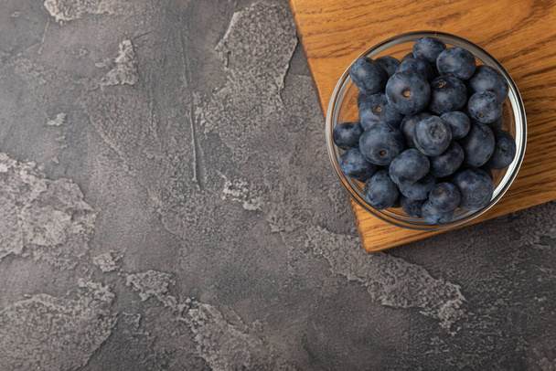 Blueberries in a ceramic bowl on a black textured background. Ripe and fresh blueberries. Vitamins. Healthy food. Juicy berry.Copy space.Place for text - 写真・画像