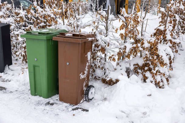 Close up view of waste and recycling containers against backdrop of snow-covered bushes in front of private villa. Sweden. - Foto, Bild