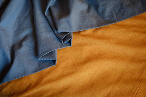 Διχρωμία φόντο γκρι και πορτοκαλί ύφασμα, πτυχώσεις τσαλακωμένο ύφασμα, επιλεκτική εστίαση - Φωτογραφία, εικόνα