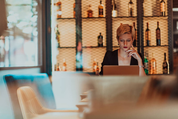 Businesswoman sitting in a cafe while focused on working on a laptop and participating in online meetings. Selective focus. High quality photo.  - Foto, imagen