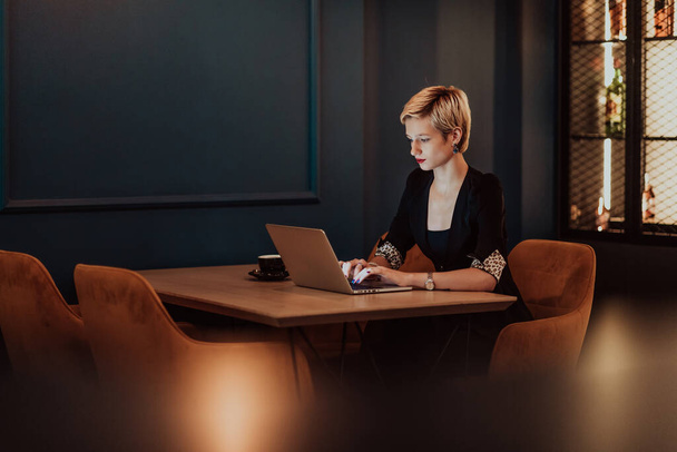 Businesswoman sitting in a cafe while focused on working on a laptop and participating in online meetings. Selective focus. High quality photo.  - 写真・画像