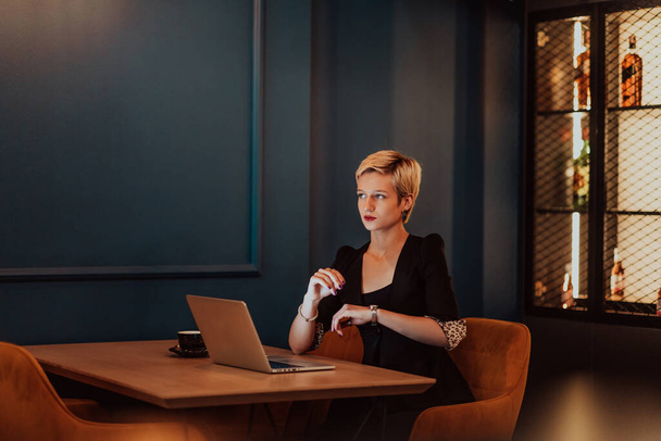 Businesswoman sitting in a cafe while focused on working on a laptop and participating in online meetings. Selective focus. High quality photo.  - Fotoğraf, Görsel
