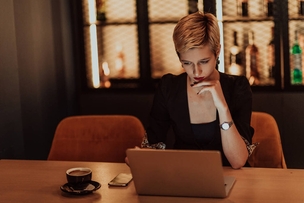 Businesswoman sitting in a cafe while focused on working on a laptop and participating in online meetings. Selective focus. High quality photo.  - 写真・画像