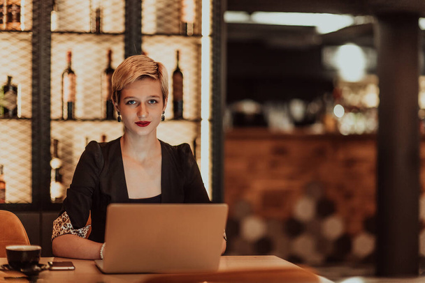 Businesswoman sitting in a cafe while focused on working on a laptop and participating in online meetings. Selective focus. High quality photo.  - Foto, Imagem