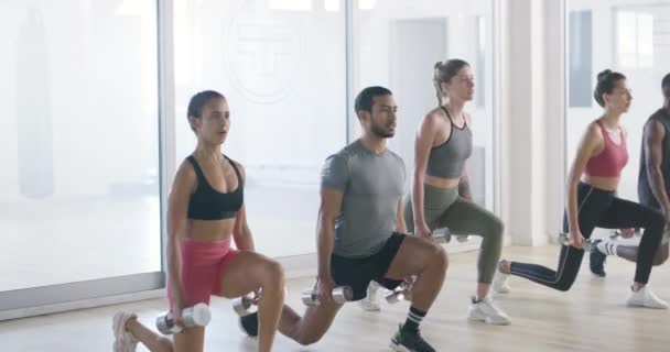 Group of fit, active and athletic diverse people exercising together in a health club or class in a gym. Team of athletes doing the leg lunges exercise or workout for fitness and cardio training. - Filmati, video