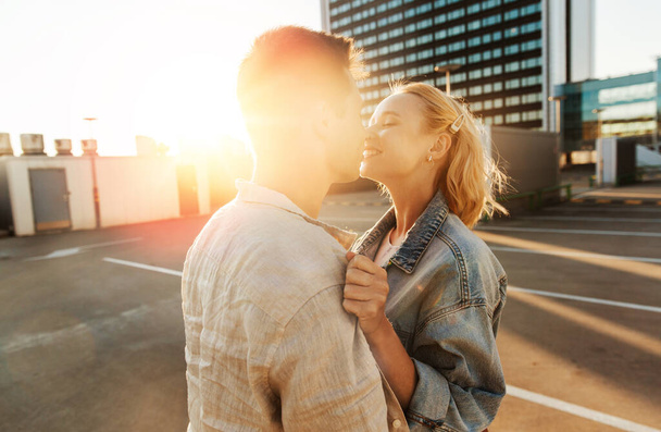 summer holidays, love and people concept - happy young couple hugging on roof top city parking - Фото, изображение