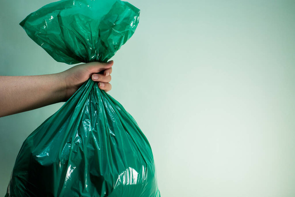 Hand holding a green plastic bag on green background - Fotoğraf, Görsel