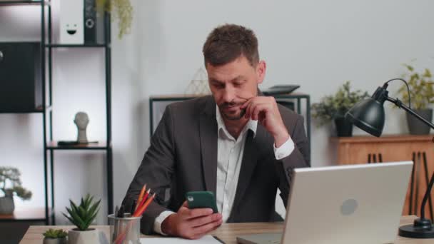 Бізнесмен-програміст розробник програмного забезпечення в костюмі, що працює в офісі, закінчуючи телефонним дзвінком, що продається в Інтернеті за допомогою смартфона, роблячи жест перемоги, отримуючи хороші новини, радіючи успіху тріумфу
 - Кадри, відео