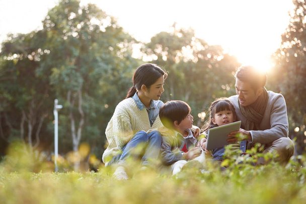 famiglia asiatica con due bambini rilassarsi all'aperto nel parco della città - Foto, immagini