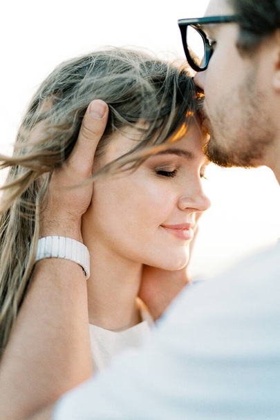 Man kisses woman on the forehead, holding her head in his hands. Portrait. High quality photo - Foto, imagen