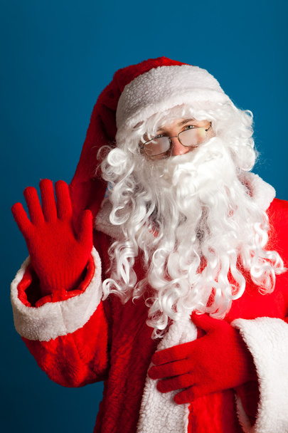 Santa Claus met rode kostuum zwaaien met hand - Foto, afbeelding