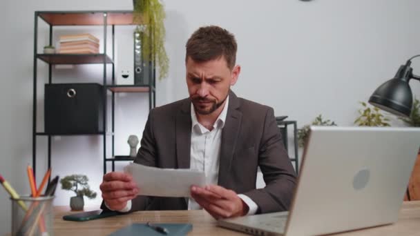 Stressed businessman in suit working looking at unpaid bank debt bills, doing paperwork, planning budget, calculate finances mortgage payments at office. Displeased freelancer man throws paper bills - Materiaali, video
