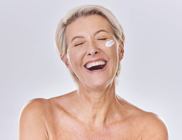Sunscreen, lotion and moisturizing senior woman with face cream on skin isolated on studio background. Beauty, fresh and aging lady with wrinkles applying moisturizer for selfcare or skincare routine. - Fotografie, Obrázek