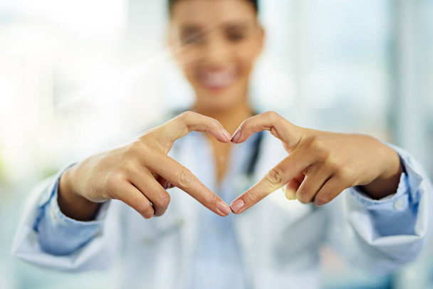The greatest wealth comes from an investment in your health. Portrait of a young female doctor making a heart shape with her fingers - Foto, Imagem