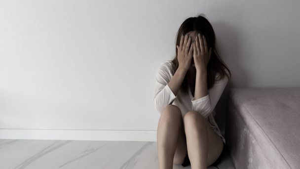 Young person woman sad, stress and loneliness sitting in dark room, Unhappy and crying teenage girl from domestic violence, An adult female expresses feelings of despair, anxiety from harassment. - Foto, Bild