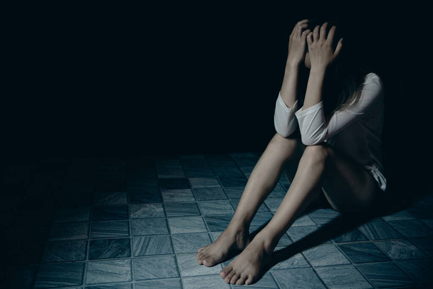 Young person woman sad, stress and loneliness sitting in dark room, Unhappy and crying teenage girl from domestic violence, An adult female expresses feelings of despair, anxiety from harassment. - Foto, imagen