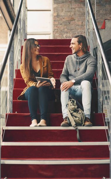 Chatting on campus. Full length shot of two young university students studying while sitting on a staircase on campus - Foto, Imagem