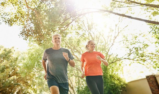 Staying fit together. a mature couple out jogging on a sunny day - Foto, Imagem