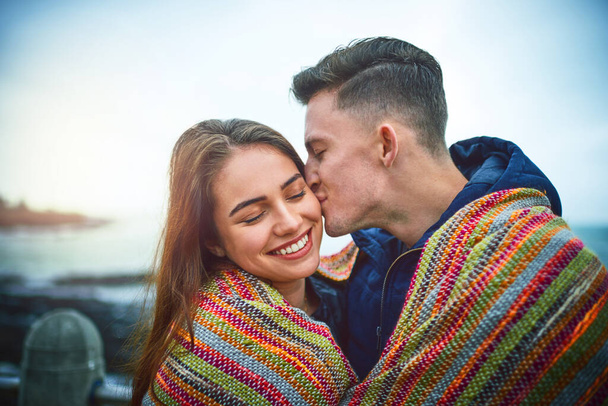 Kisses for my honey bunny. a happy young couple covering themselves with a blanket outdoors - Fotoğraf, Görsel