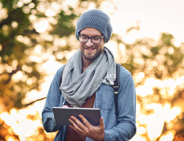 This helps me find the sites I want to explore. a handsome young man using a tablet outdoors - Photo, image