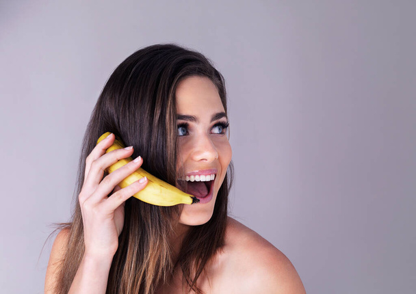 У мене є новини, які змусять вас піти з бананами. Студійний знімок привабливої молодої жінки, яка вдає, що використовує банан як телефон на фіолетовому фоні
 - Фото, зображення