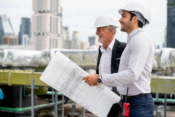 Два техника или профессиональные инженеры выражают свое счастье во время совместной работы на крыше строительной площадки. - Фото, изображение